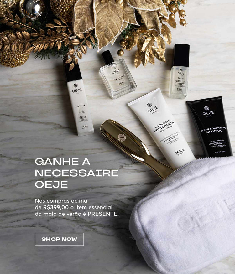 Vários produtos OEJE (shampoo, condicionador, leave-in, perfume), escova dourada e nécessaire branca, com fundo de mármore e enfeites dourados.