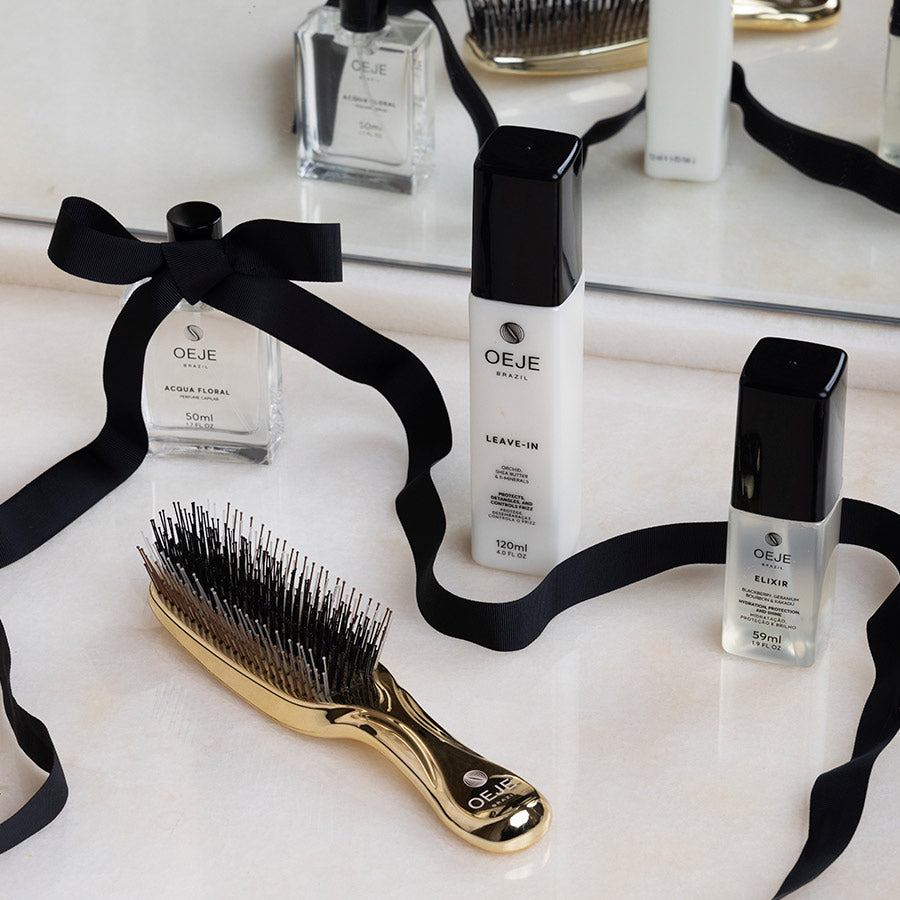 Exposição de produtos OEJE BRAZIL: leave-in, elixir, Acqua Floral e escova de cabelo dourada, arranjados com fita preta.